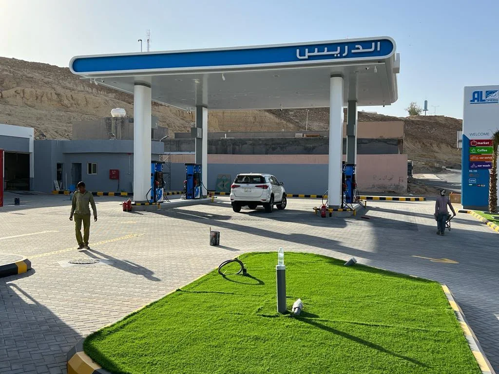 Daytime commercial forecourt with paved circulation, service canopy and vertical signage