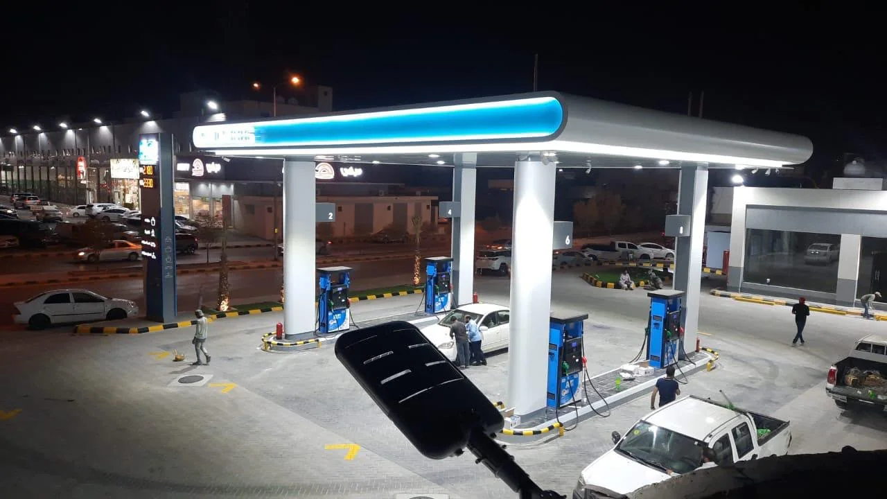 Night operation under a lit canopy with directional ground markings and price totem